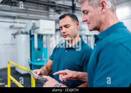 Mature male engineers working on digital tablet together in factory Stock Photo