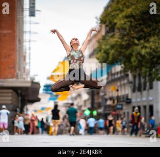 Elegant ballet dancer dancing with hand raised on street in city Stock Photo