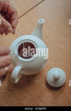 Woman's hands preparing tea in kettle on kitchen table Stock Photo