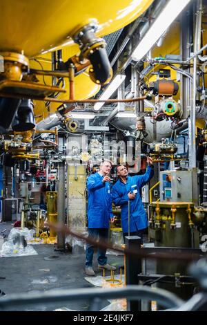 Engineers in overalls working on machinery equipment in industry Stock Photo