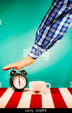 Arm of woman turning off old-fashioned alarm clock Stock Photo