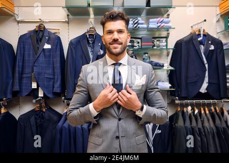 Portrait of smiling man in gray suit in tailors boutique Stock Photo