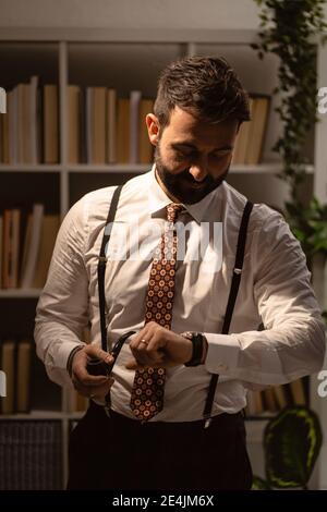 Portrait of bearded man checking time with smoking pipe in hand Stock Photo
