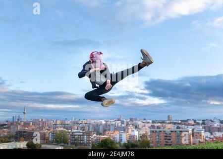 Male professional wearing pig mask practicing kickboxing while jumping against sky Stock Photo