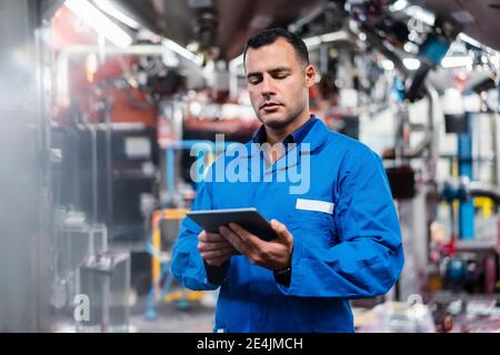 Engineer in blue coat working on digital tablet in factory Stock Photo