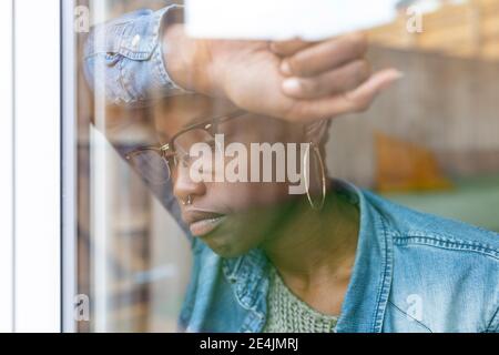 Sad woman looking through window Stock Photo