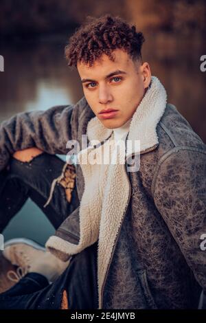 Fashionable young man with blue eyes on jetty against lake Stock Photo