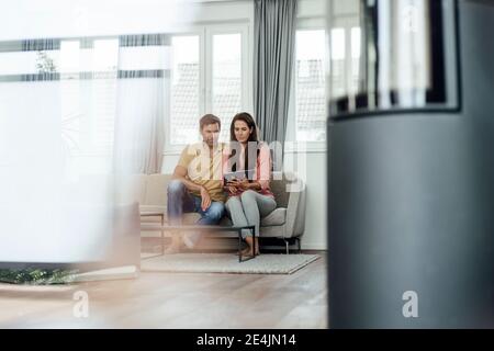 Mature couple using digital table while sitting on sofa in apartment Stock Photo