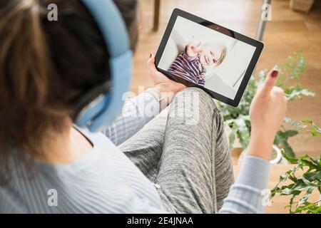 Mother showing thumbs up to daughter on video call through digital tablet Stock Photo