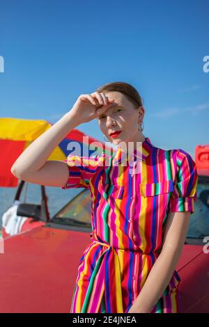 Beautiful woman standing by car at beach on sunny day Stock Photo