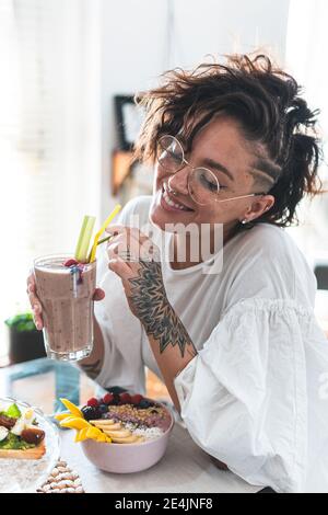 Portrait of young woman smiling while enjoying fruit smoothie for breakfast Stock Photo