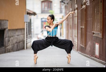 Female dancer dancing while standing tiptoe on footpath Stock Photo