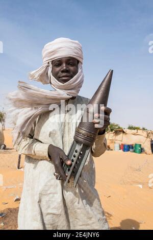 Young Man posing with an old rockethead, between Faya-Largeaux and N'Djamena, Sahara, Chad Stock Photo