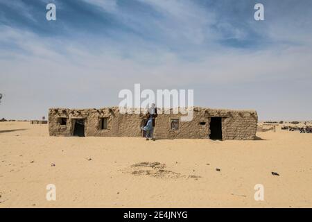 Man in front of traditional mud house, a village in the desert, between Faya-Largeaux and N'Djamena, Sahara, Chad Stock Photo
