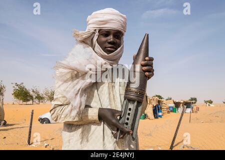 Young Man posing with an old rockethead, between Faya-Largeaux and N'Djamena, Sahara, Chad Stock Photo