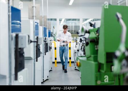 Male professional working on digital tablet while walking in industry Stock Photo