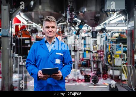 Mature engineer holding digital tablet while standing in industry Stock Photo