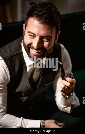 Portrait of bearded man laughing while smoking pipe Stock Photo