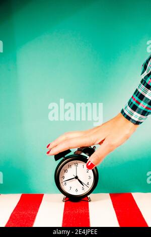 Hand of woman turning off old-fashioned alarm clock Stock Photo