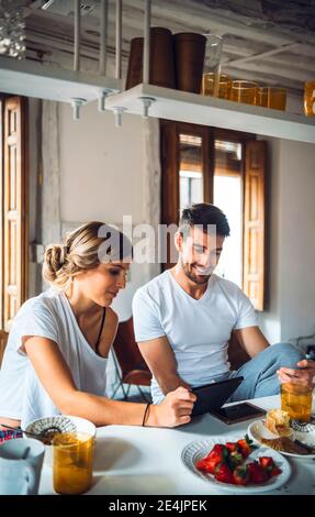 Young couple watching tablet while having breakfast at home Stock Photo