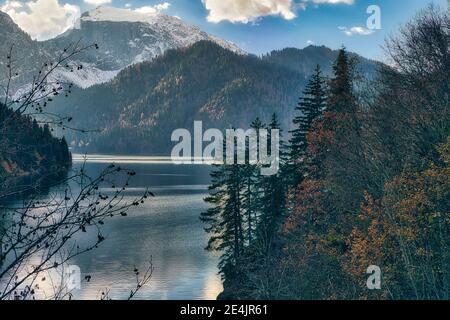 Lake Ritsa surrounded by forested mountains in autumn, Abkhazia, Georgia Stock Photo