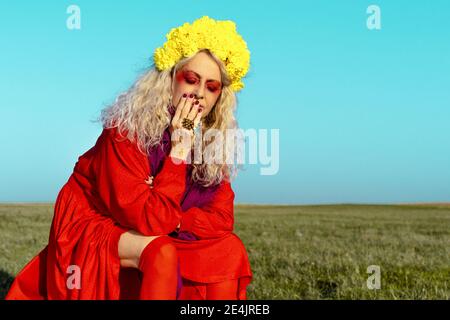 Woman with eyes closed sitting against blue sky Stock Photo