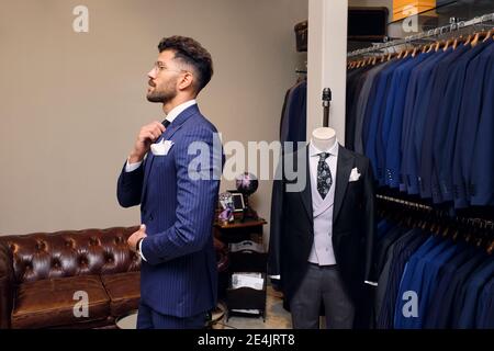 Man trying on blue pinstripe suit in tailors boutique Stock Photo