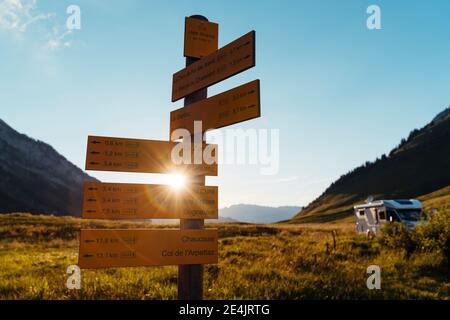 Signs indicating mountain routes with motor home during sunset at Col des Aravis;Haute-Savoie, Stock Photo