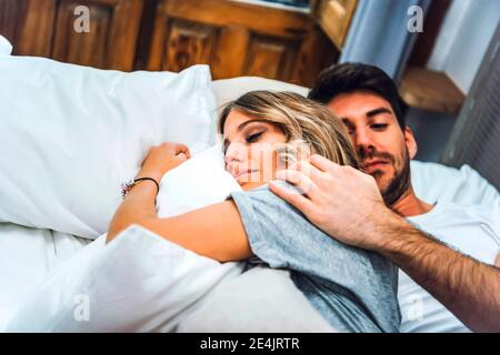 Affectionate young couple lying in bed at home Stock Photo