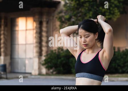 Determined woman tying hair while exercising in park Stock Photo
