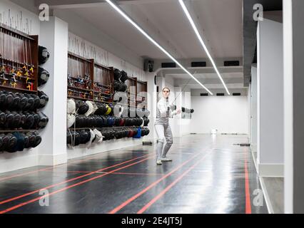 Woman in fencing outfit practicing at gym Stock Photo