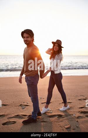 Young couple holding hands while walking on beach Stock Photo