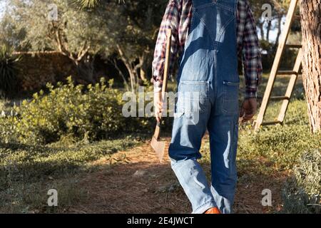 Man walking with axe on sunny day Stock Photo