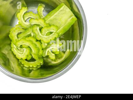 Close up bitter gourd or bitter melon in stainless steel bowl, isolated on white background, top view image fresh bitter gourd, small cut pieces and o