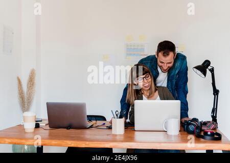 Smiling business couple working together on laptop at home office Stock Photo
