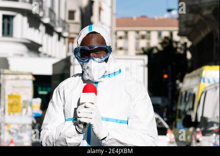 Male presenter wearing protective suit with microphone standing in city Stock Photo