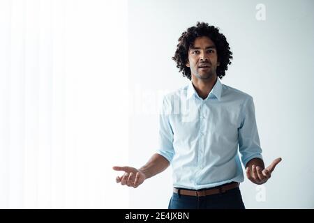Confident young handsome male entrepreneur giving presentation against white wall at office Stock Photo
