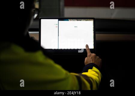 Male electric vehicle technician programming on digital tablet in car Stock Photo