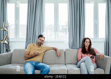 Mature woman using phone while man looking at nails at home Stock Photo