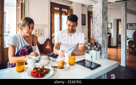 Young couple sitting at table and having breakfast at home Stock Photo