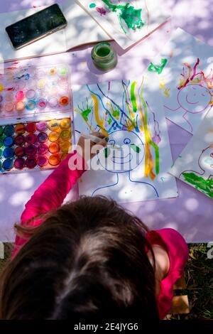 Girl painting with watercolors on paper in yard Stock Photo