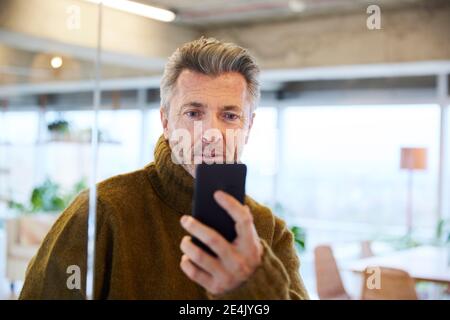 Surprised man looking at mobile phone at home Stock Photo