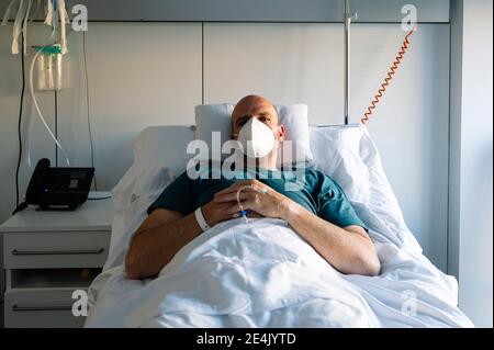 Patient wearing protective face mask sleeping on bed in hospital Stock Photo