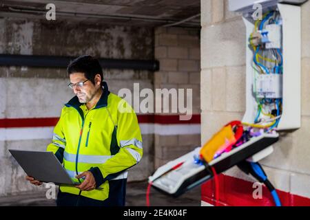 Mature technician programming on laptop at auto repair shop Stock Photo