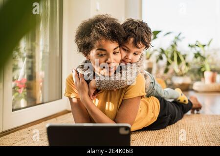 Mother and son using digital tablet while lying at home Stock Photo