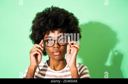 Woman wearing eyeglasses while standing against green background Stock Photo