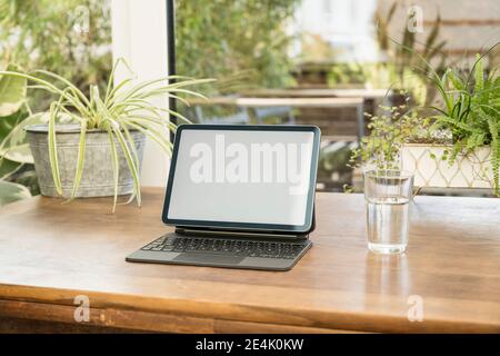 Digital tablet with keyboard by glass on table at home Stock Photo