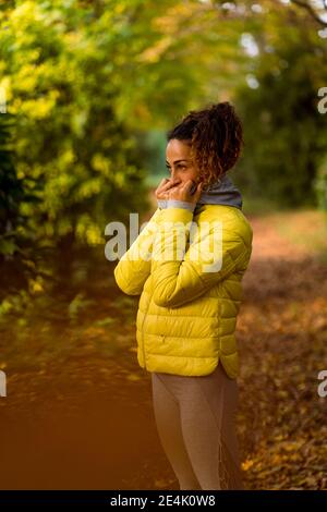 Sportswoman wearing hooded shirt looking away while standing at park Stock Photo