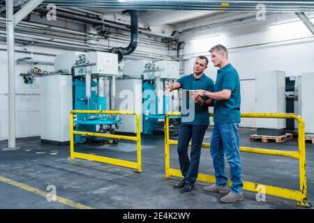 Engineers planing strategy over digital tablet in factory Stock Photo