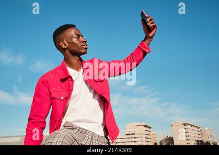 Young man in red jacket taking selfie outdoors Stock Photo